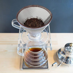 V-format kaffefilter med malet kaffe placerat i en separat filterhållare över en glaskanna